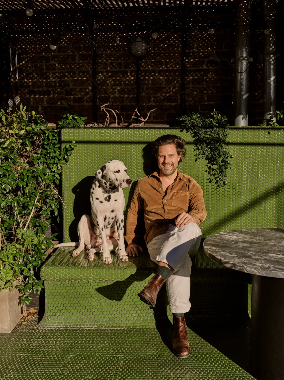 Louis Denavaut i jego suczka rasy damatin Poppy na słonecznym tarasie na dachu. Senne Van der Ven